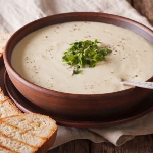 White vegetable cream soup close-up on the table. horizontal